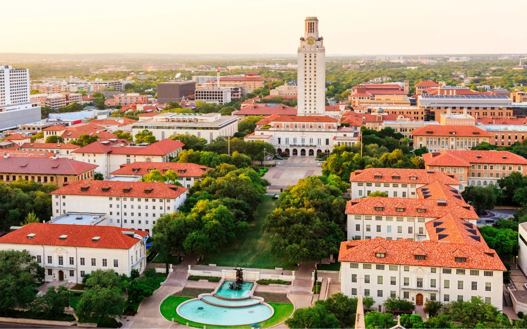Aerial view of a university campus at sunset, its clock tower at the center.