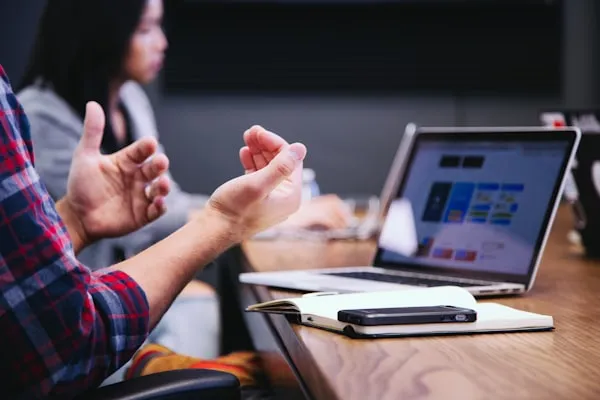 An instructor gestures toward a laptop during a planning discussion.