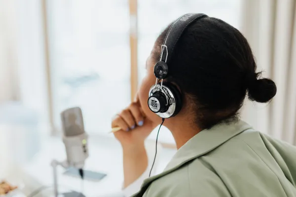 A student wearing headphones listens beside a studio microphone.